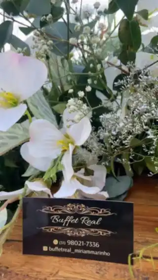 Arranjo floral com o cartão do Buffet Real